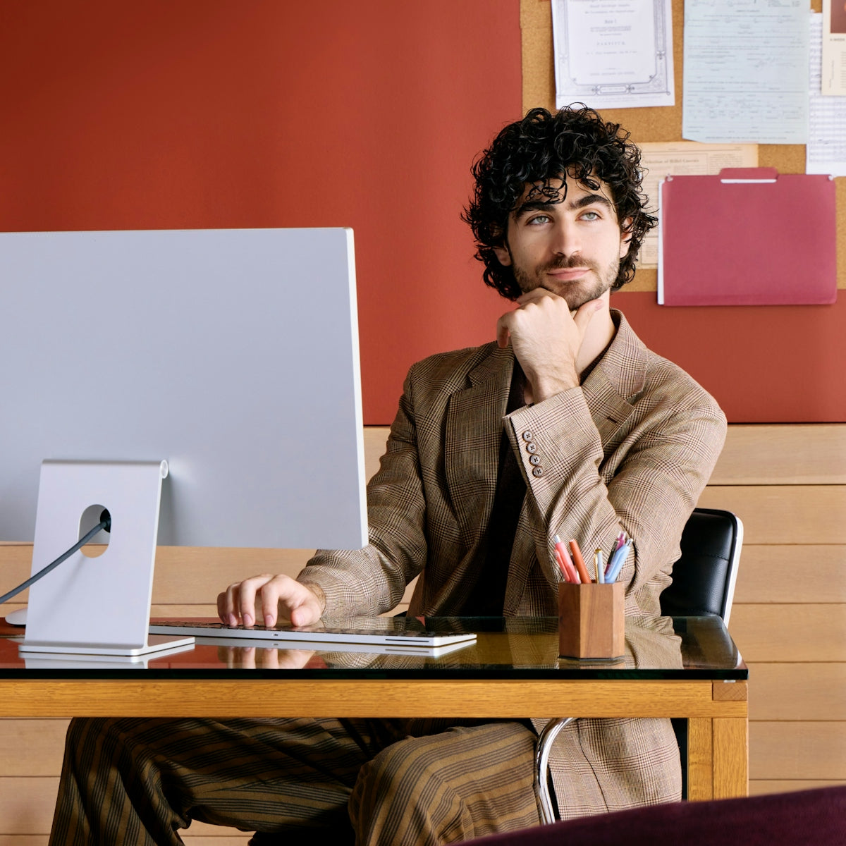 Man sitting at desk with computer, resting chin