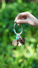 Mint green wrapped seed charm with turquoise beads and shell tassels held outdoors