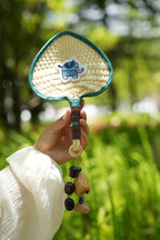 "The Lucky Breeze" - Hand - Woven Heart Palm Fan with Blue Elephant & Seed Charm - Yunicrafts