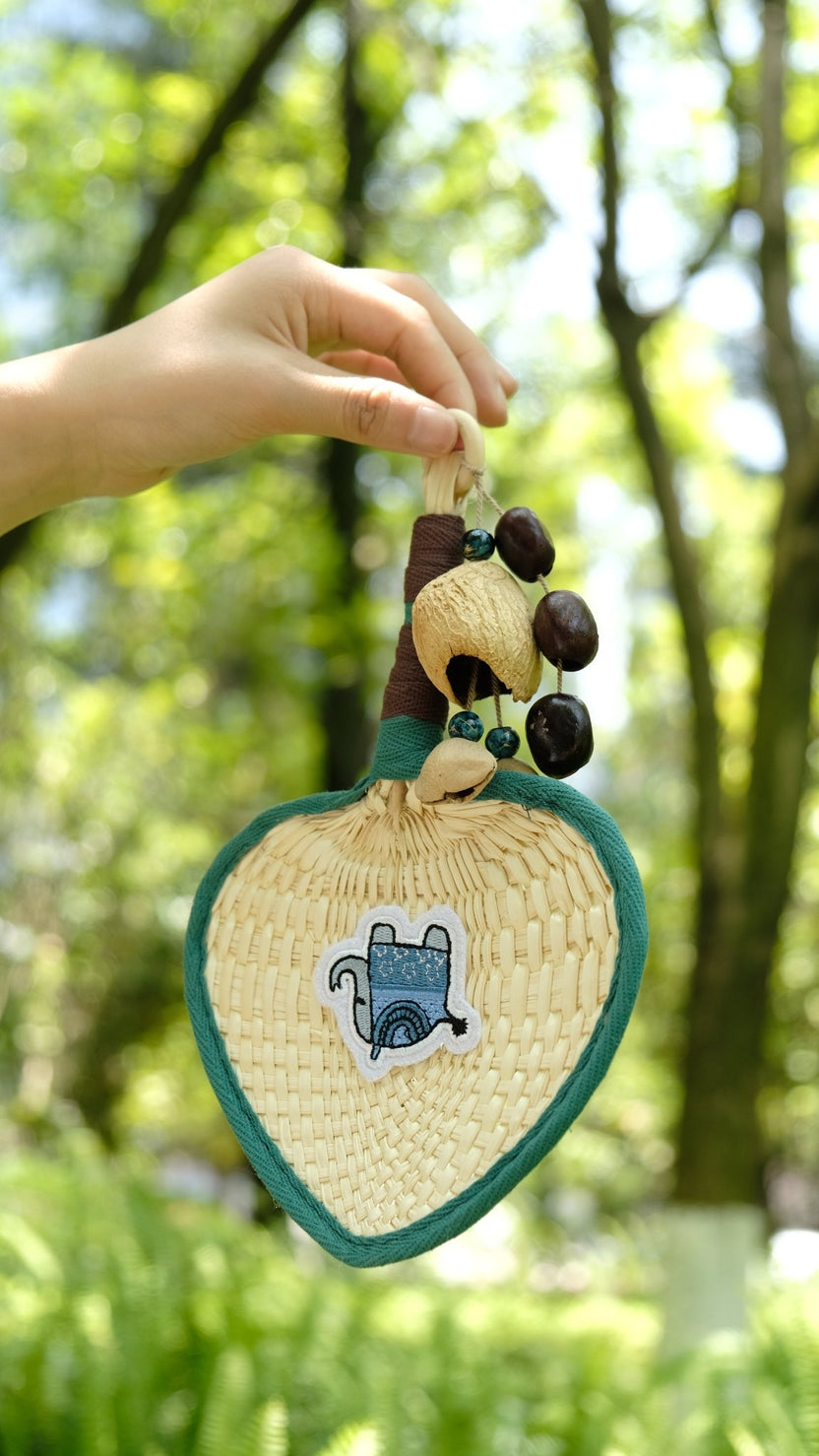 "The Lucky Breeze" - Ventaglio di palma con cuore intrecciato a mano con elefante blu e ciondolo con semi - Yunicrafts